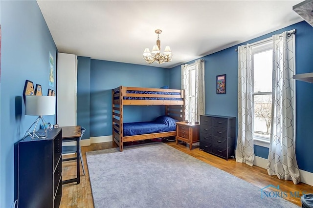 bedroom with a notable chandelier, multiple windows, baseboards, and wood finished floors