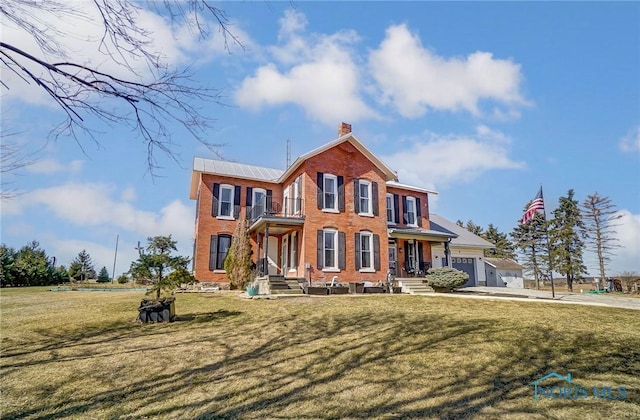 view of front facade with a balcony, a chimney, a front lawn, a garage, and brick siding