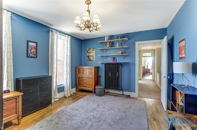 interior space featuring an inviting chandelier, radiator, wood finished floors, and baseboards