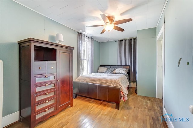 bedroom with baseboards, light wood-style floors, and a ceiling fan