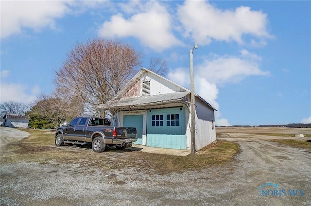 view of front facade featuring metal roof, a garage, and an outdoor structure