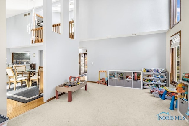 game room with visible vents, baseboards, a high ceiling, and carpet