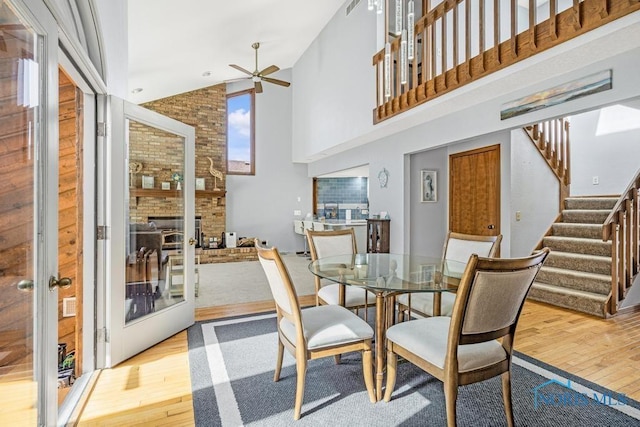 dining space with stairs, hardwood / wood-style flooring, a ceiling fan, and a towering ceiling