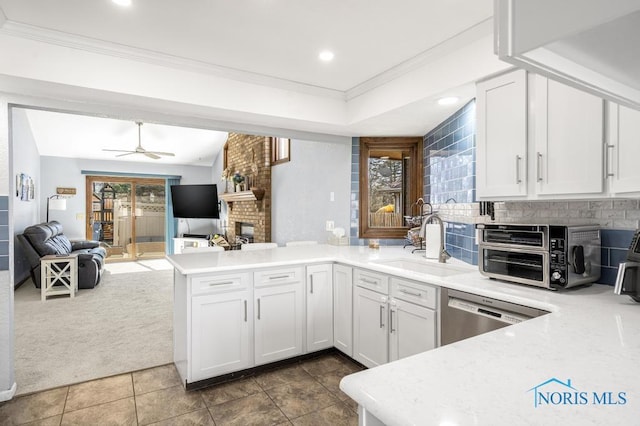 kitchen with a sink, stainless steel dishwasher, a peninsula, and light countertops