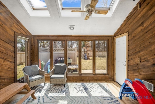 sunroom / solarium with visible vents, vaulted ceiling with skylight, and a ceiling fan