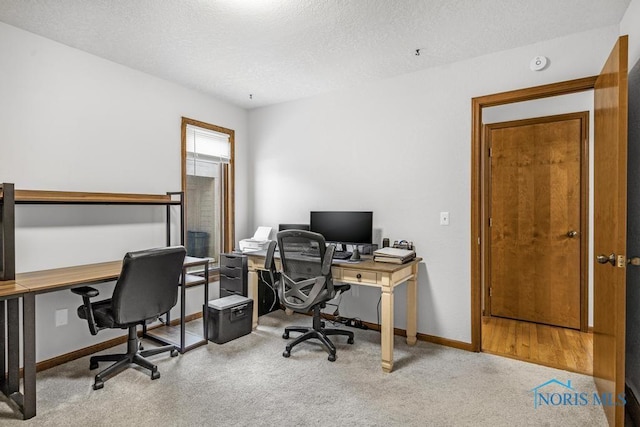 carpeted office featuring baseboards and a textured ceiling