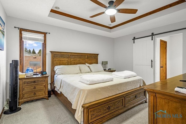 bedroom with a tray ceiling, a barn door, light colored carpet, and ceiling fan