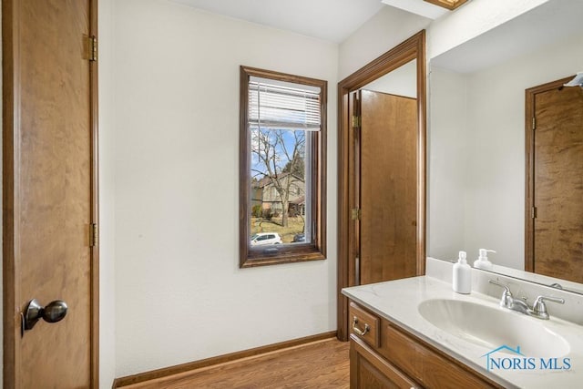 bathroom featuring vanity, wood finished floors, and baseboards