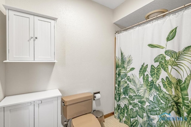 full bath featuring curtained shower, toilet, and baseboards