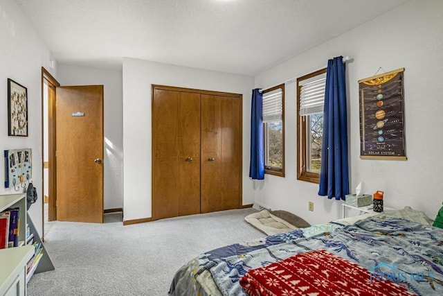 carpeted bedroom featuring baseboards and a closet