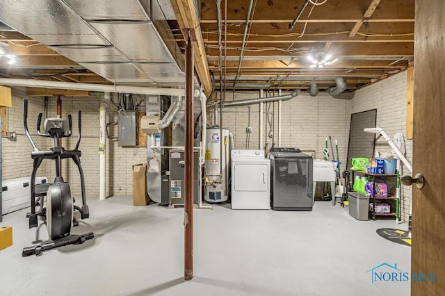 unfinished below grade area featuring brick wall, electric panel, water heater, a sink, and washing machine and dryer