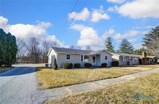 ranch-style home with central air condition unit, a front lawn, and driveway