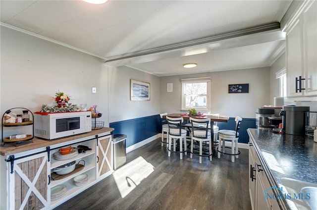 kitchen featuring white cabinetry, dark wood-style floors, white microwave, and ornamental molding