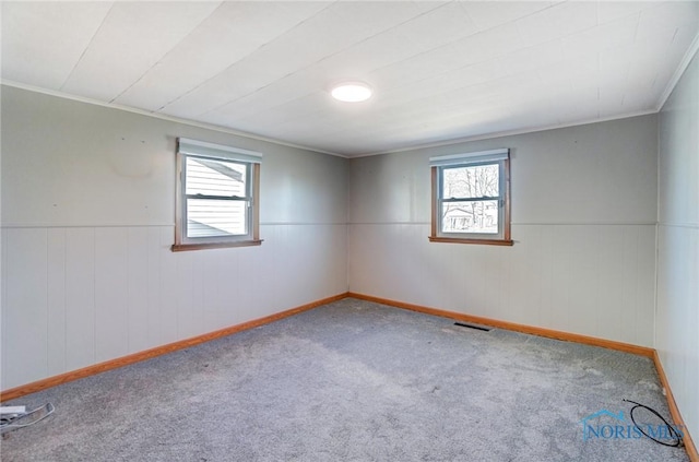 spare room featuring crown molding, carpet, visible vents, and a wealth of natural light