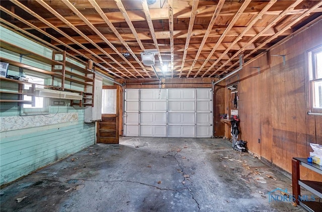 garage with a garage door opener and wood walls