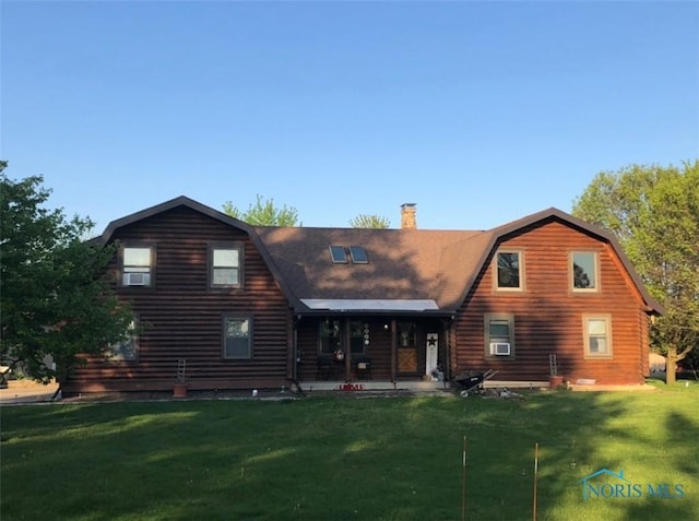 back of house with log siding, a yard, a gambrel roof, and a chimney