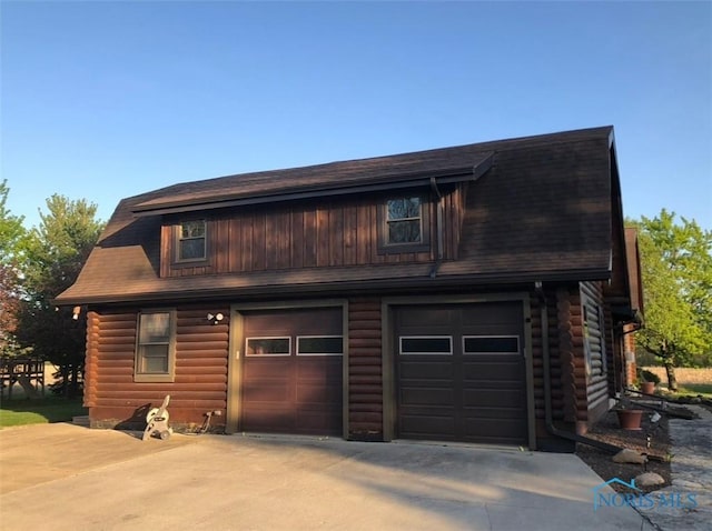 view of front of home with concrete driveway, log exterior, and an attached garage