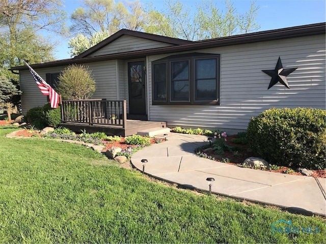 view of front facade with a deck and a front lawn