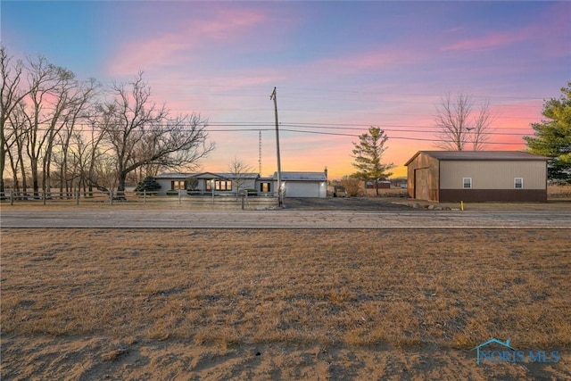 view of front facade with a detached garage, an outbuilding, and fence