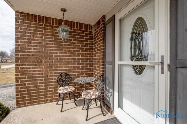 view of exterior entry featuring brick siding and a porch