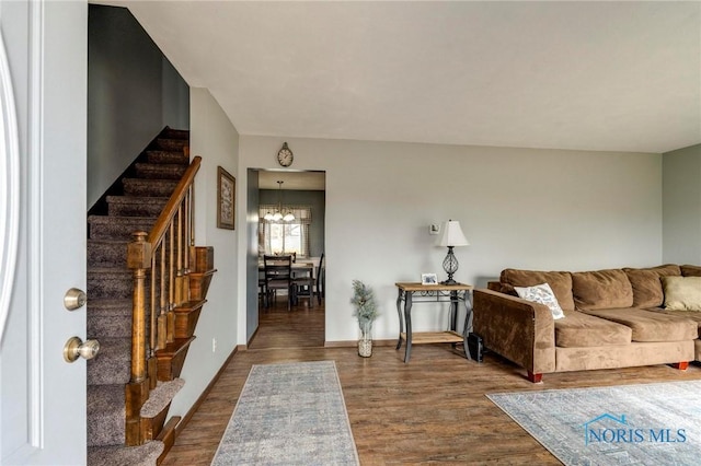 living room with a chandelier, baseboards, wood finished floors, and stairs