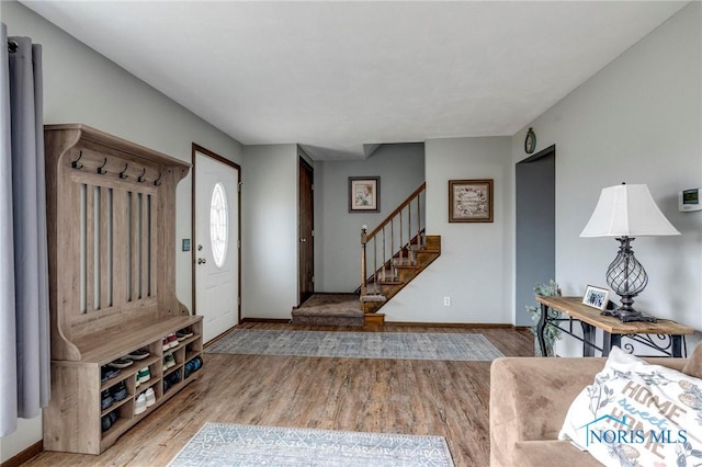 foyer entrance with stairway, baseboards, and wood finished floors