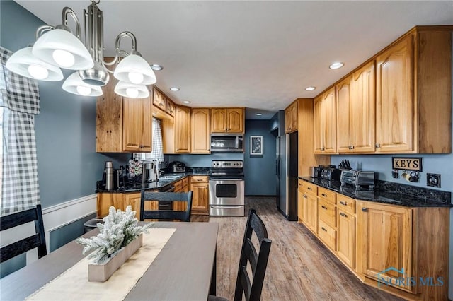 kitchen with pendant lighting, dark stone counters, recessed lighting, appliances with stainless steel finishes, and light wood-style floors