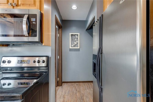 kitchen featuring light wood finished floors, stainless steel appliances, and baseboards