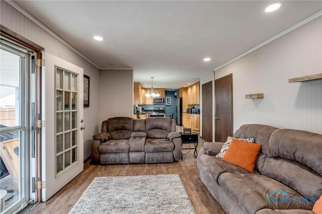 living room featuring recessed lighting, a notable chandelier, crown molding, and light wood finished floors