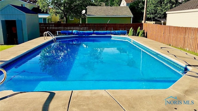 view of swimming pool featuring a shed, a fenced in pool, an outdoor structure, and a fenced backyard