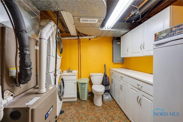 washroom featuring visible vents, stacked washer and dryer, laundry area, heating unit, and a sink