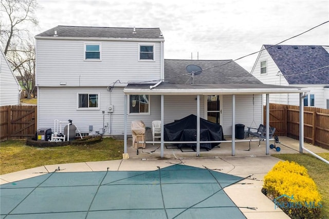 rear view of house featuring a fenced in pool, roof with shingles, a yard, a fenced backyard, and a patio area