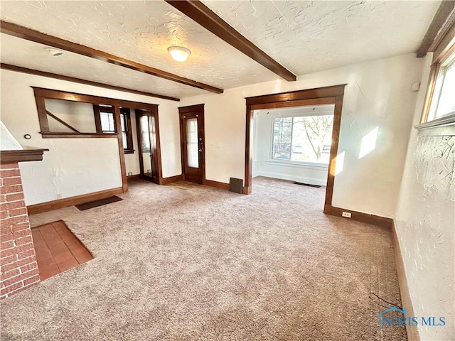 unfurnished living room with beam ceiling, carpet, baseboards, and a textured ceiling