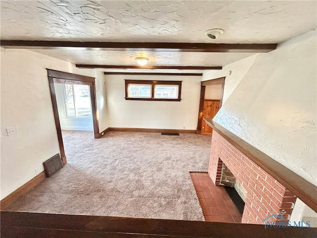 unfurnished living room featuring beam ceiling, a fireplace, carpet floors, and a textured ceiling