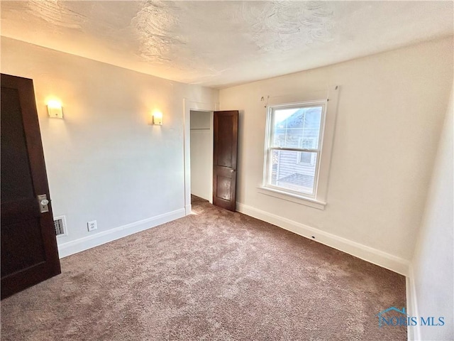 unfurnished bedroom featuring visible vents, baseboards, a textured ceiling, and carpet flooring