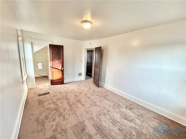 unfurnished bedroom featuring baseboards, carpet floors, and visible vents