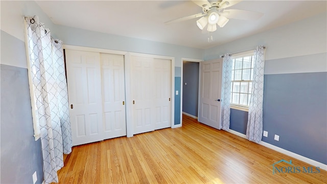 unfurnished bedroom with wood finished floors, baseboards, and two closets