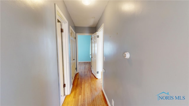 corridor featuring light wood-style flooring and baseboards