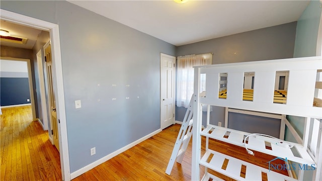 bedroom with a closet, baseboards, attic access, and hardwood / wood-style floors