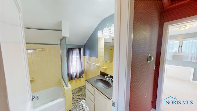 bathroom with wallpapered walls, tile walls, a wainscoted wall, shower / tub combination, and vanity