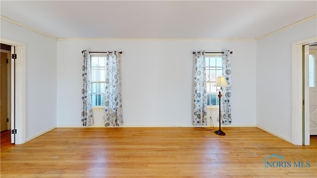 spare room with wood finished floors, baseboards, and ornamental molding