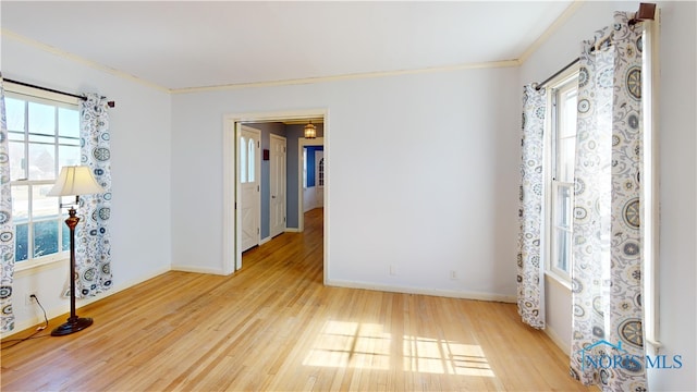 empty room featuring crown molding, wood finished floors, and baseboards