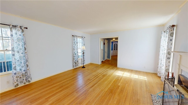 unfurnished living room featuring crown molding, wood finished floors, baseboards, and a wealth of natural light