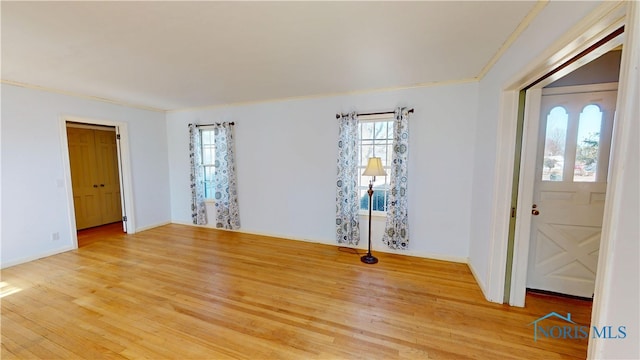 interior space with light wood-type flooring, baseboards, and crown molding