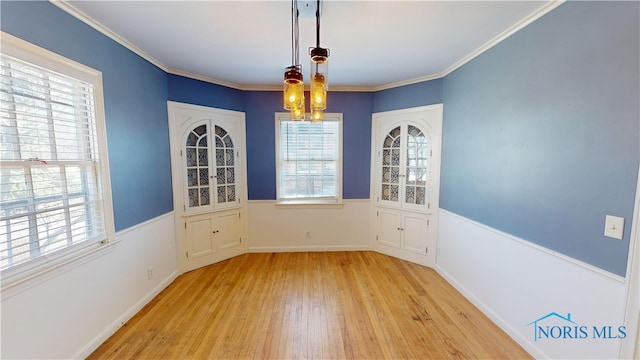 unfurnished dining area with baseboards, light wood-style floors, an inviting chandelier, and crown molding