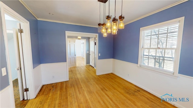 unfurnished dining area with a chandelier, wood finished floors, baseboards, and ornamental molding