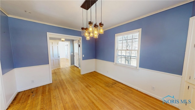 empty room with a notable chandelier, crown molding, baseboards, and wood finished floors