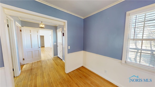 hall with light wood finished floors, crown molding, and baseboards