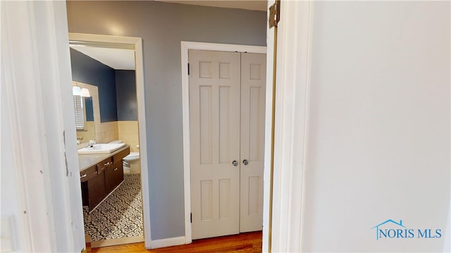 corridor with a sink, tile walls, and wood finished floors