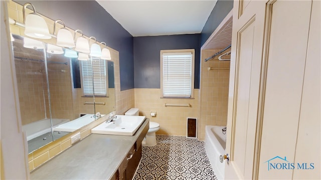 bathroom featuring tile patterned flooring, tile walls, toilet, shower / bathtub combination, and vanity